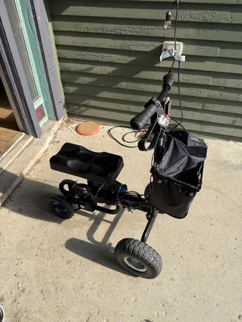 The finished knee scooter parked on a porch, blue rear wheels